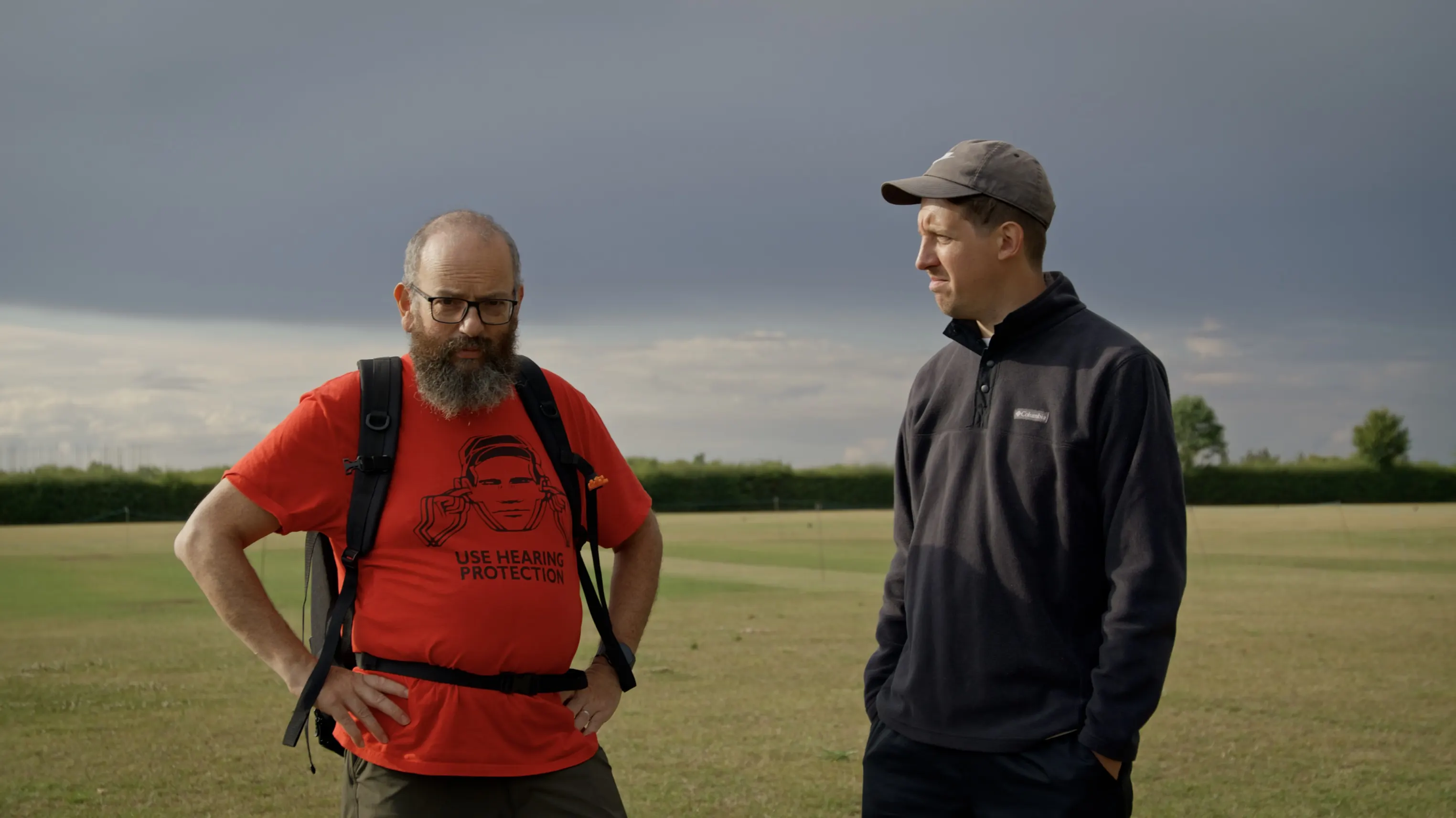 David Trent as Crab and Mark G Smith as Peter stand in a field under a darkening sky