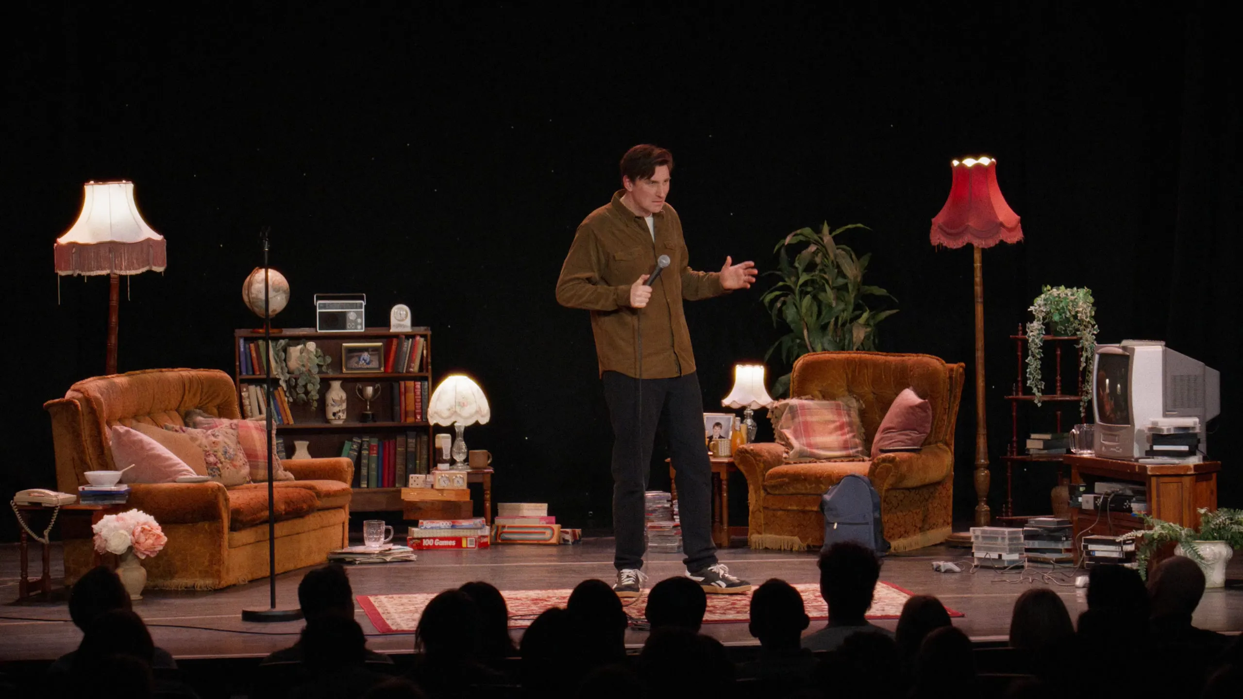 Wide of the White Elephant stage: Sean McLoughlin performs in a living room set of armchairs and fringed lamps